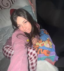 A girl in bed with a Winnie the Pooh blanket and pajamas taking a selfie