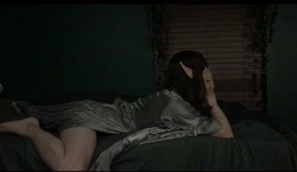 A Sexy Green Room: Featuring a Woman Laying on a Bed in a Dark Green Room with a Lamp in the Background and a Plant Behind Her