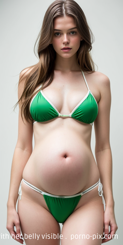 a woman in a green bikini with her belly visible . 