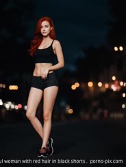 a beautiful woman with red hair in black shorts . 