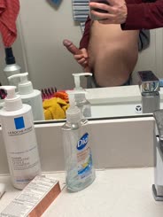 A man takes a selfie in the mirror and shows off his hairy chest and the bottle of La Roche Posay in the bathroom