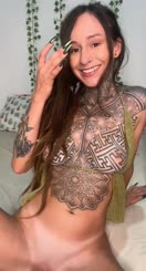 Tattooed Beauty: A Naked, Pierced, and Smiling Woman with Painted Nails